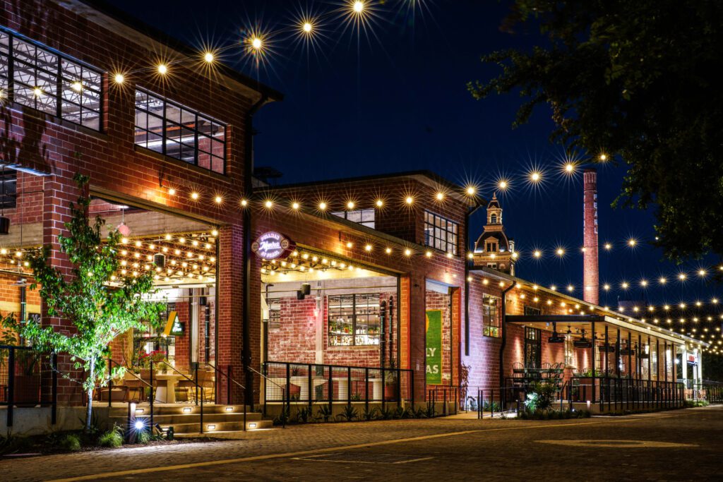 Night view of Pullman Market, showcasing modern commercial construction with restored brick architecture, ambient string lighting, and historic Pearl District charm.